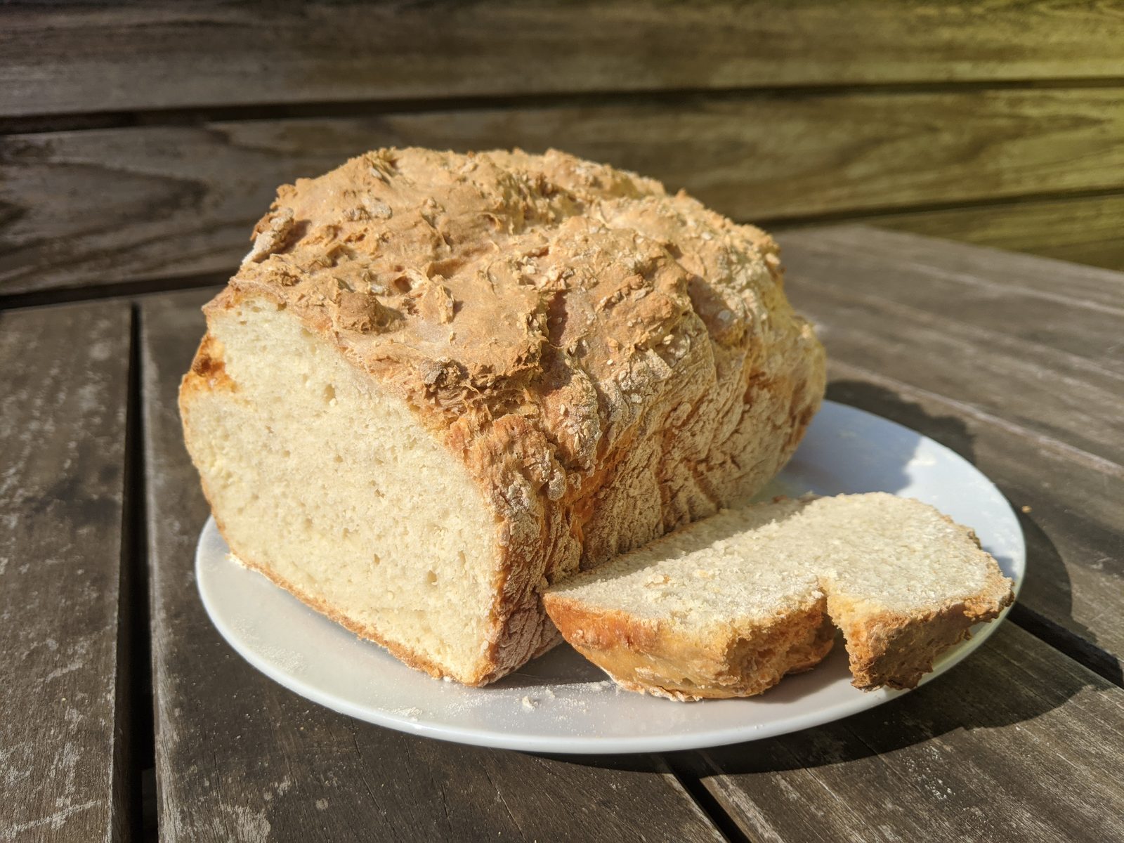 A freshly baked loaf of bread on a plate in sunlight