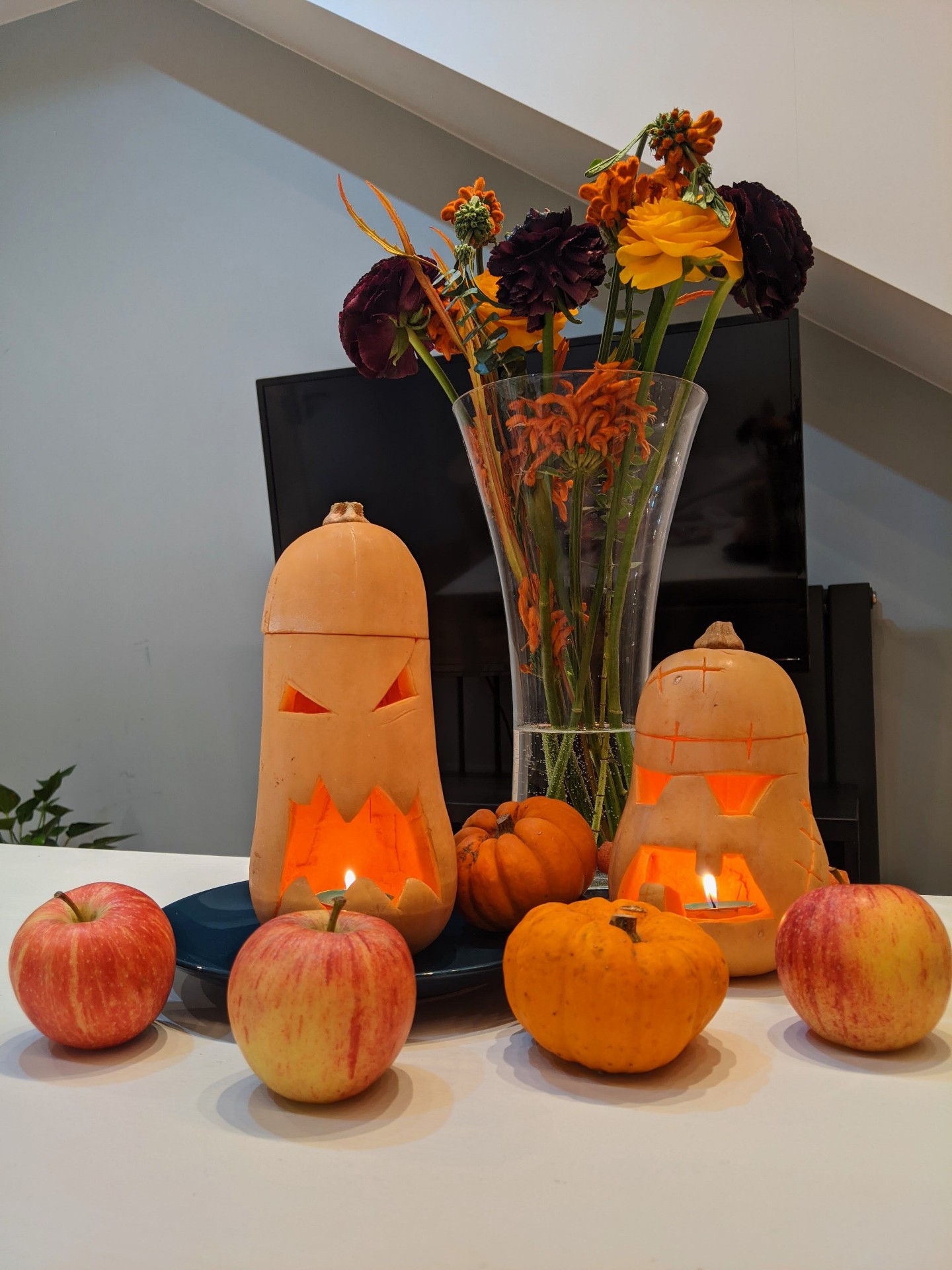 Carved butternut lanterns with apples, small pumpkins and autumn flowers